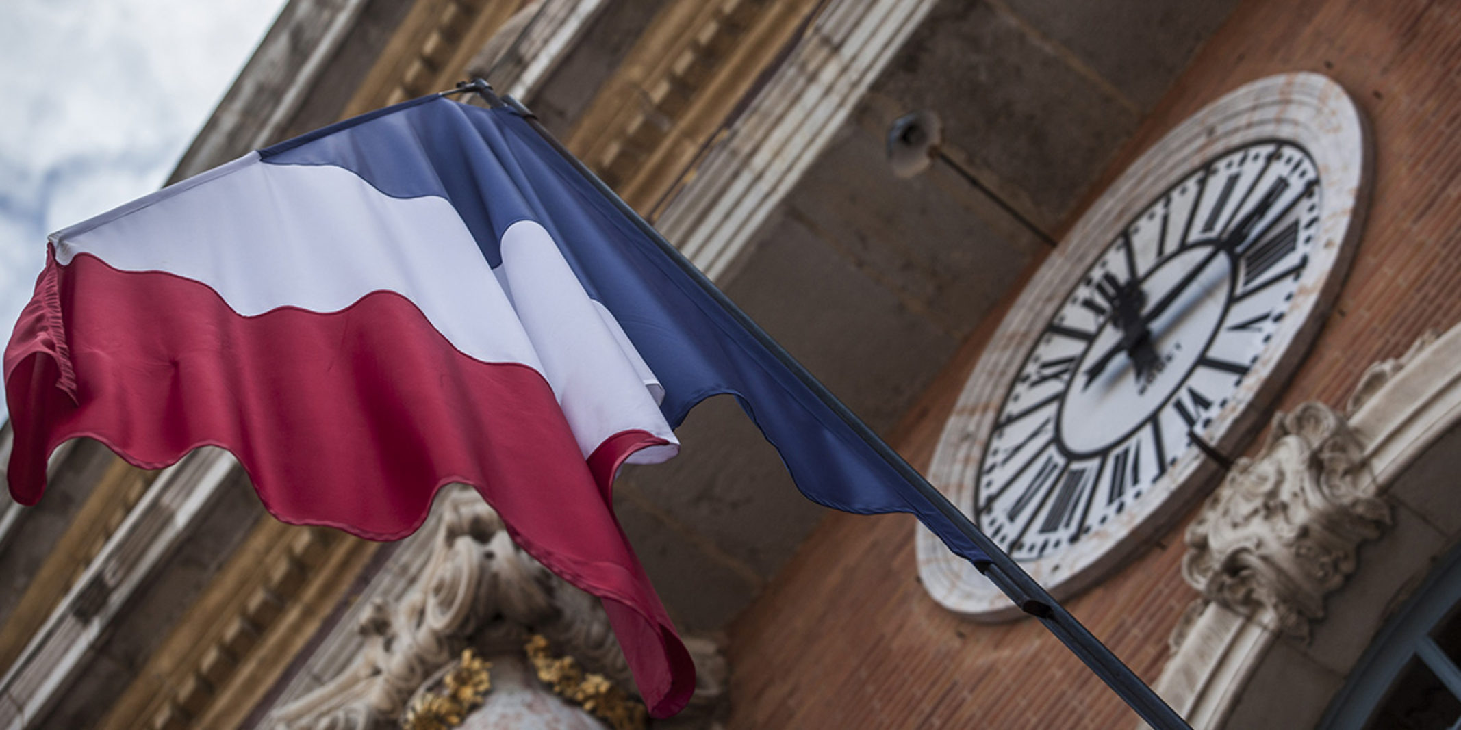 Flag of French outside a building with a giant clock