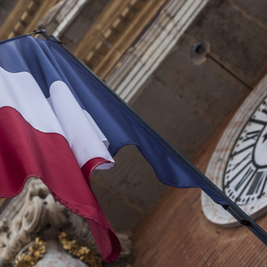 Flag of French outside a building with a giant clock