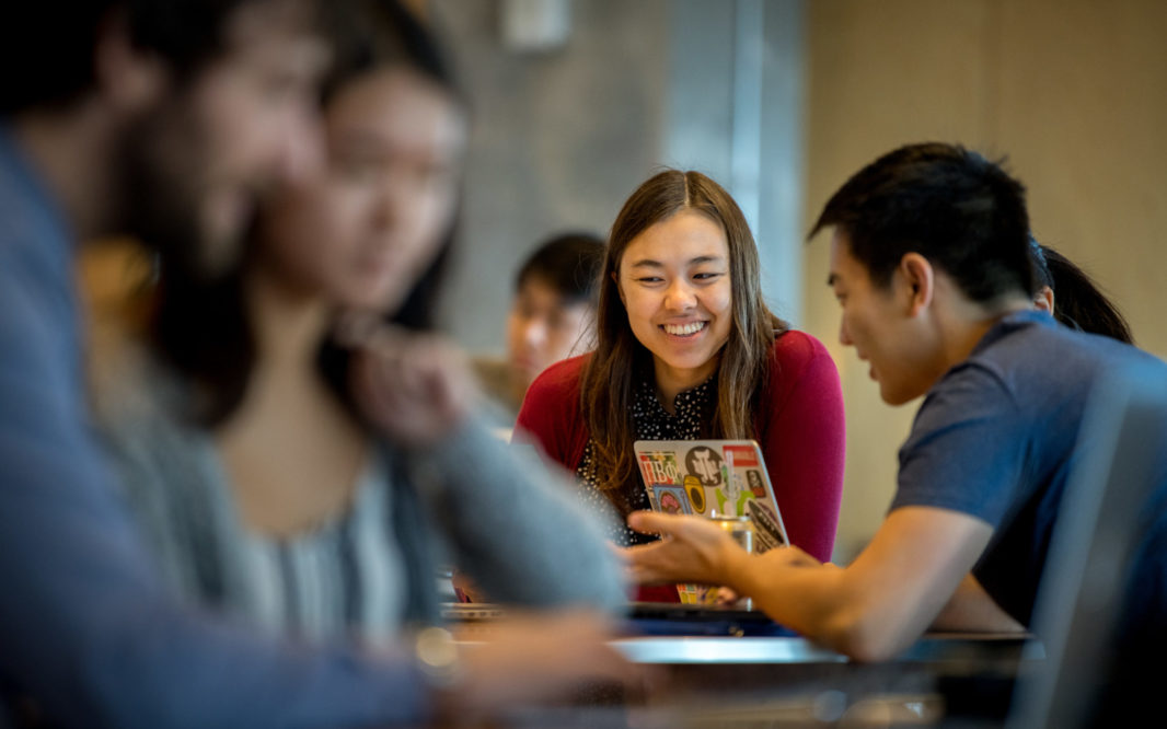 Picture of young woman in focus, having a fun and engaged conversation with her peers