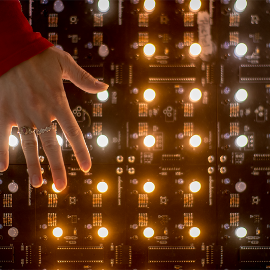 Hand in front of grid of lights on a circuit board