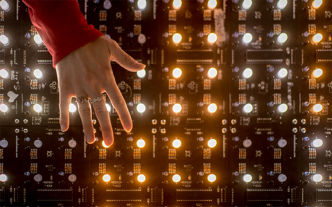 Hand in front of grid of lights on a circuit board