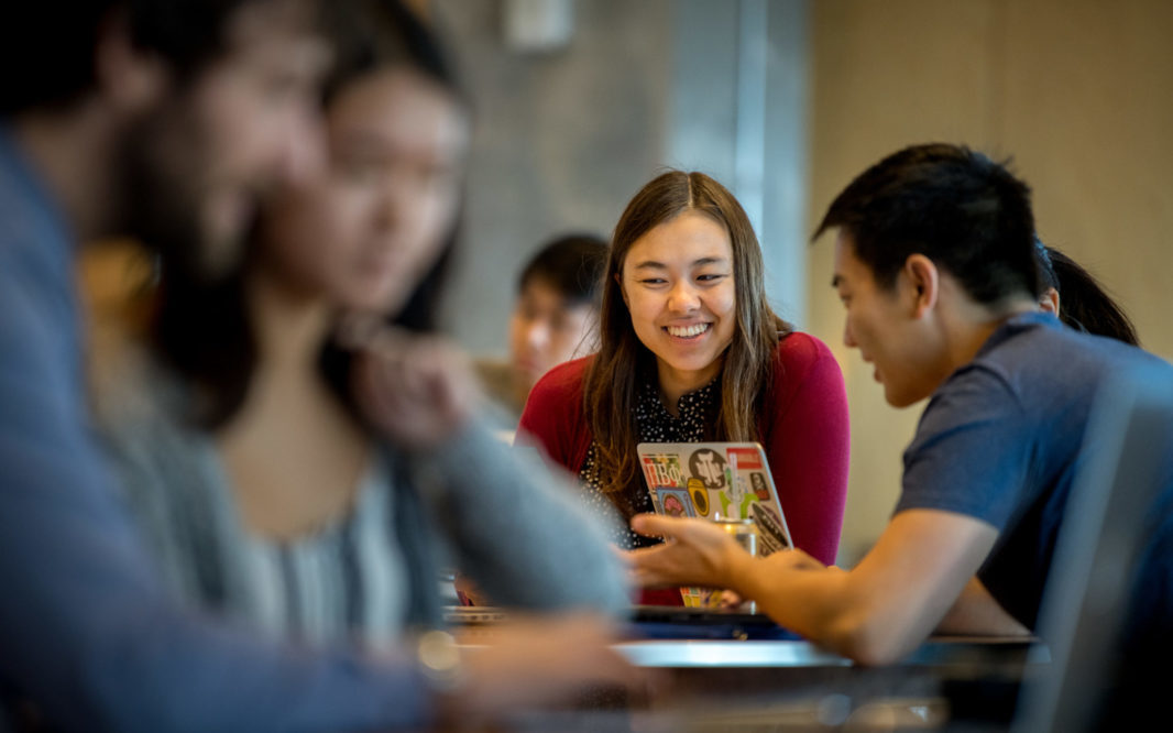 young people sitting at table laughing and talking to each other, happily