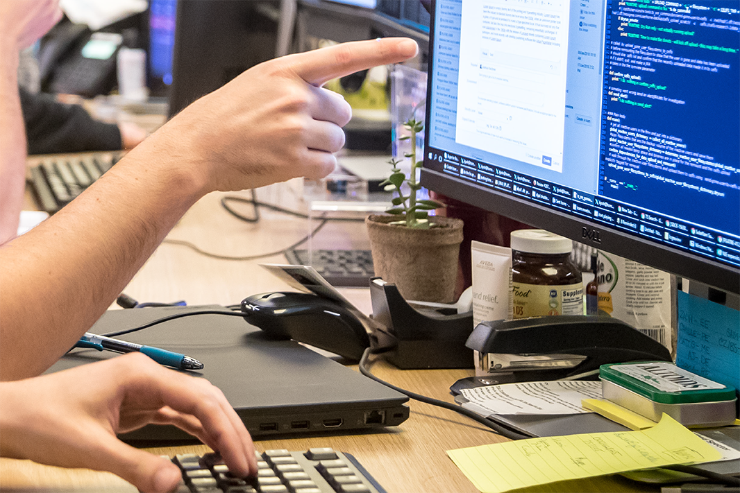 person pointing at computer screen with raw data and computer code displayed