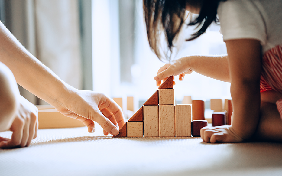 Mother and daughter stack wooden blocks.