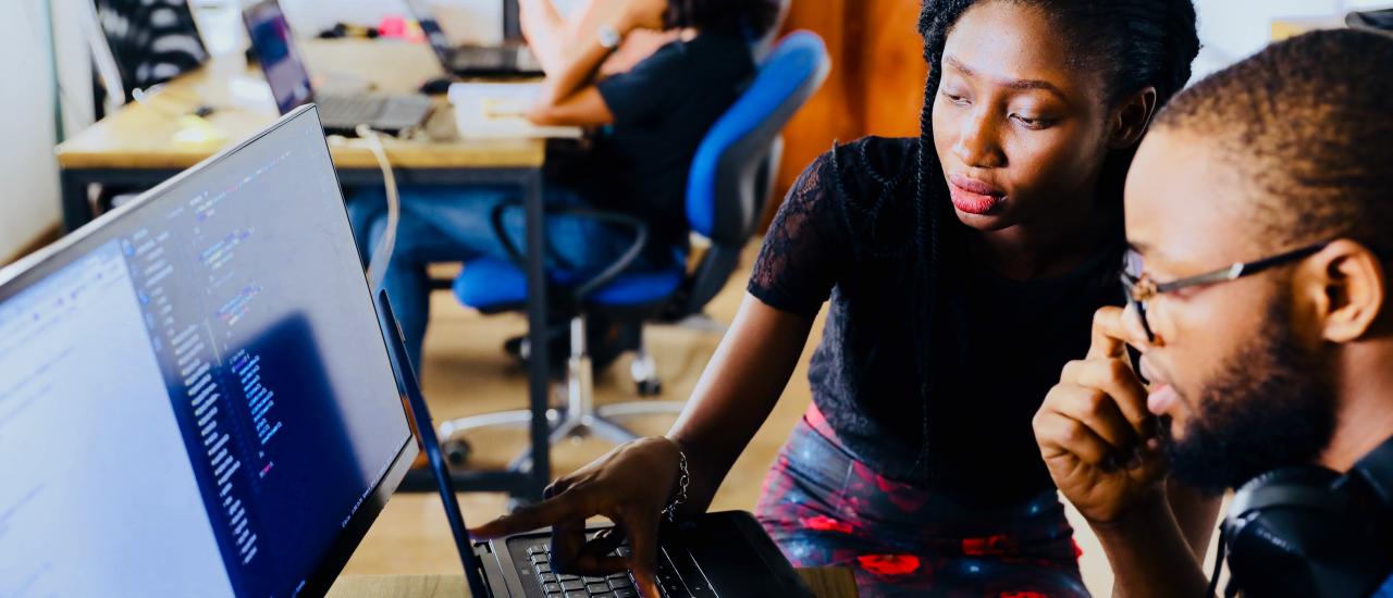 Two students work together in front of a computer.