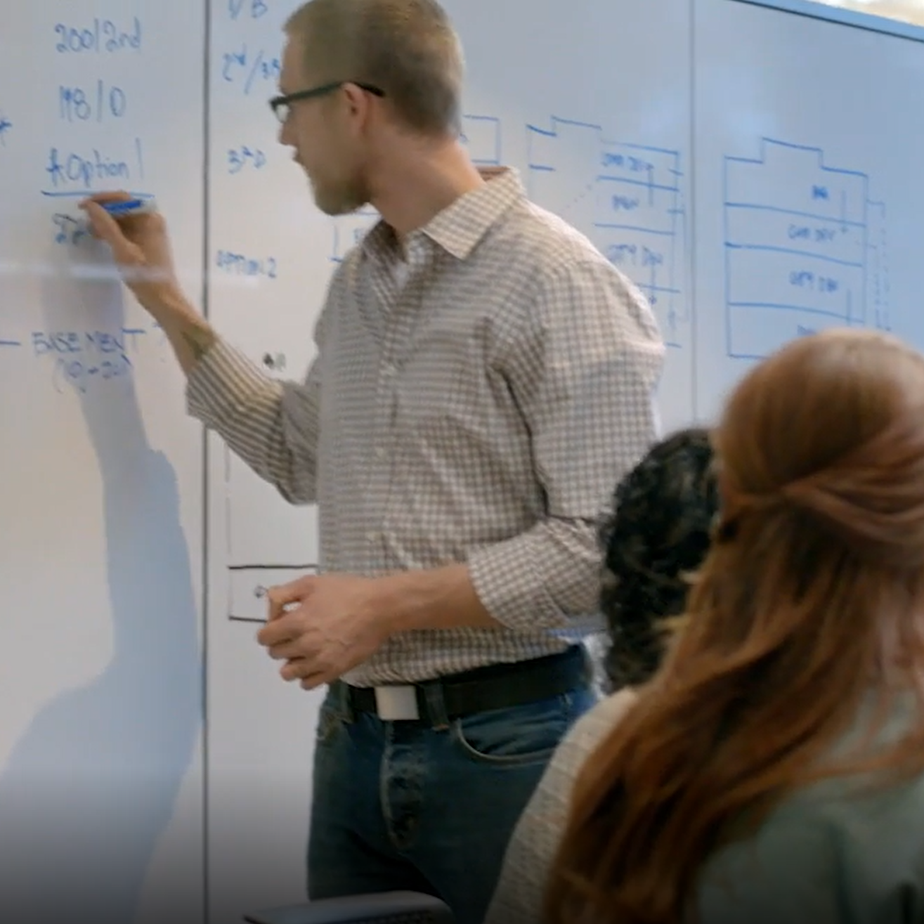 Scientist writes equation on whiteboard.