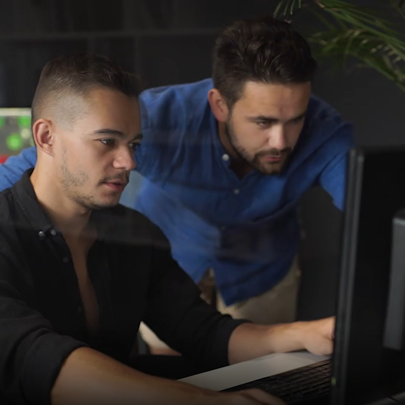 Two employees look at a computer.