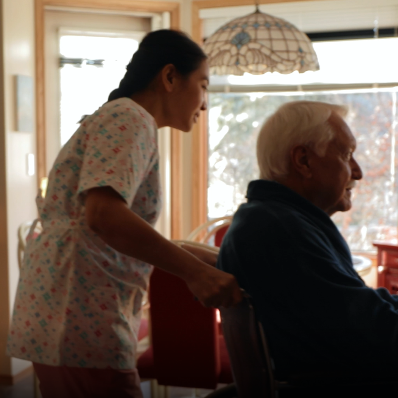 Nurse pushing an elderly man in a wheelchair.