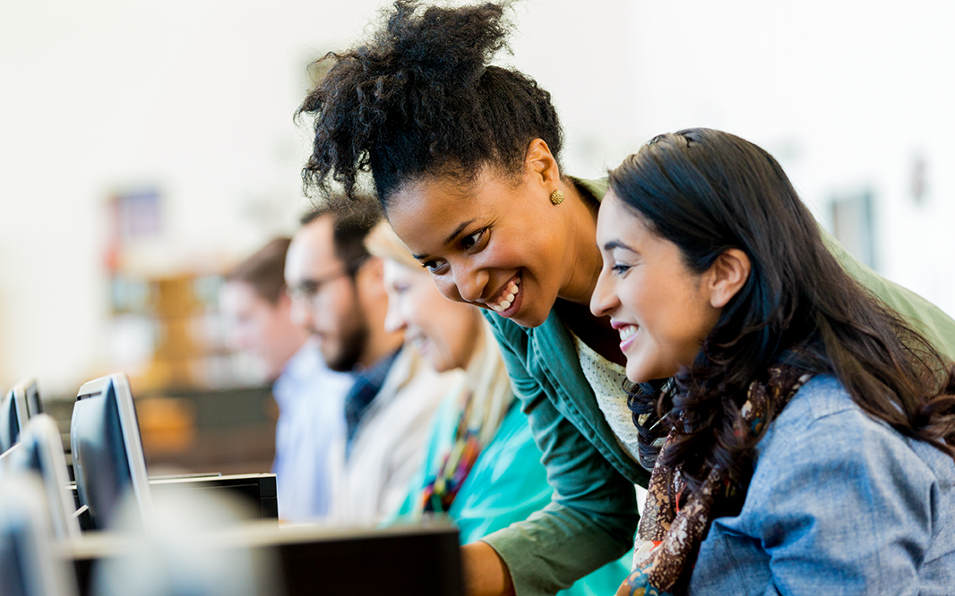 Two Sigma employee and a doctoral student work together, smiling.