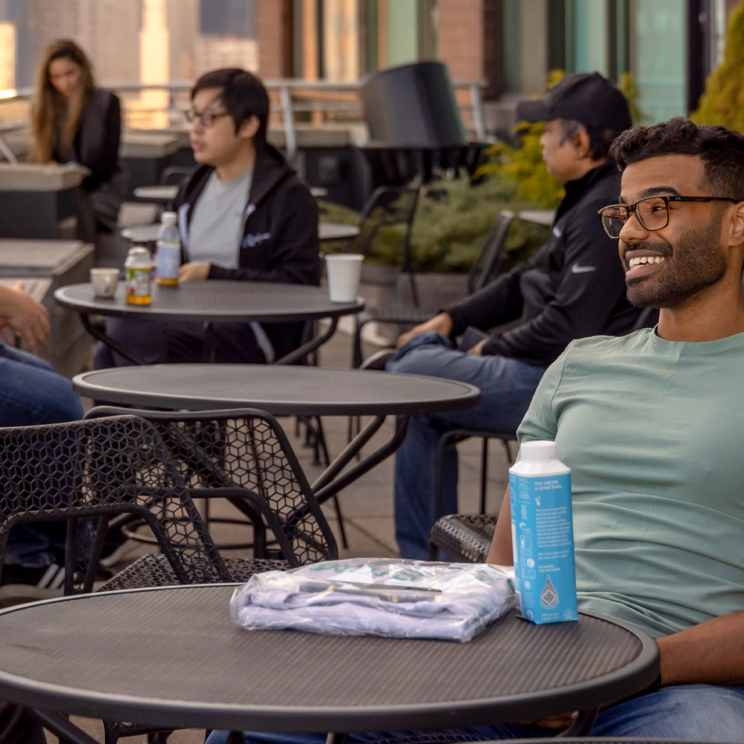 Undergraduate student sits happily outside on a college campus.