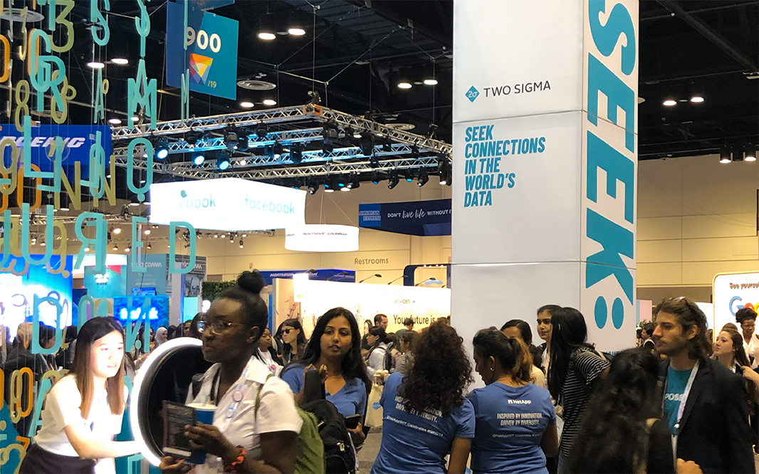 Diverse crowds of people at Two Sigma's booth at a conference.