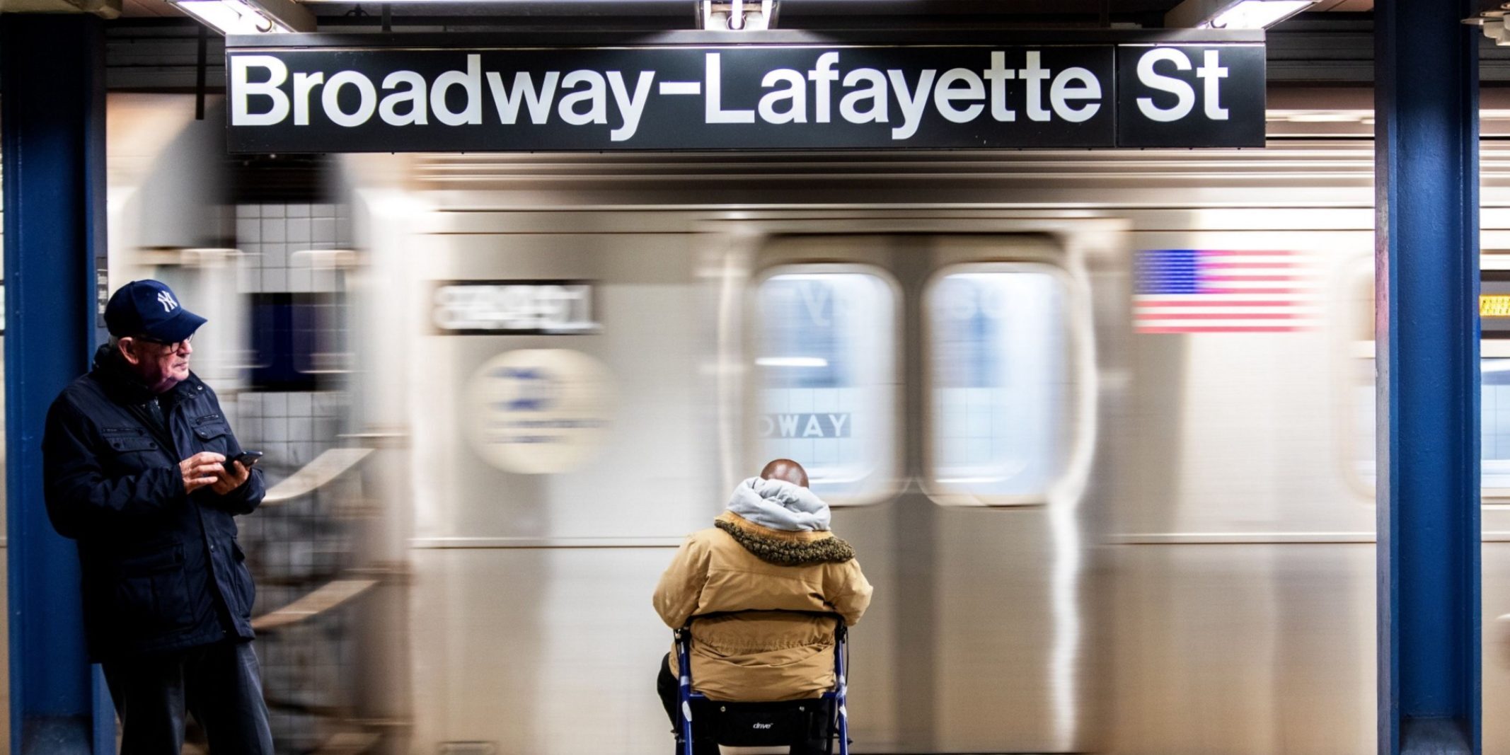 Man with a walker waits on a New York City subway platform.