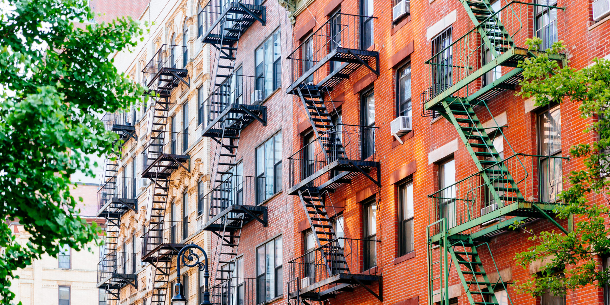 Outside of a New York City apartment building with numerous fire escapes.