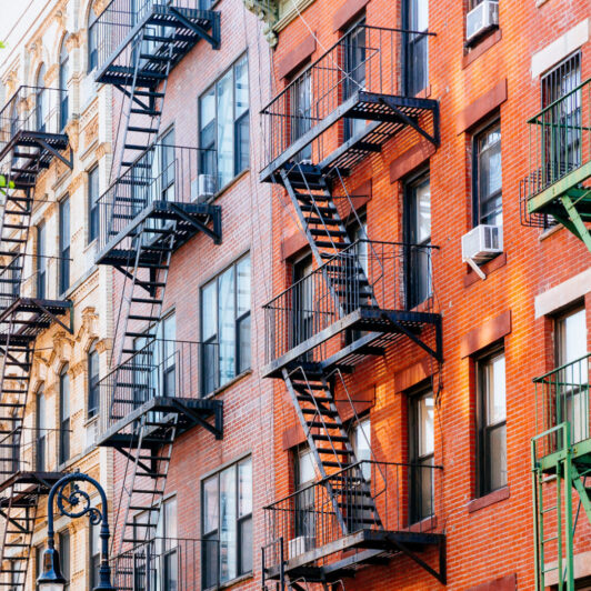 Outside of a New York City apartment building with numerous fire escapes.