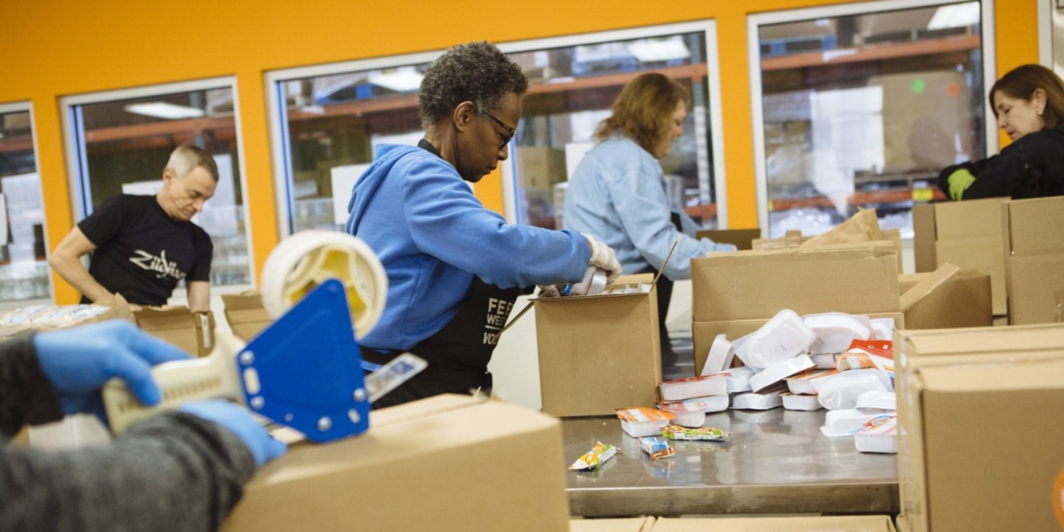 Volunteers pack boxes of food for charity.