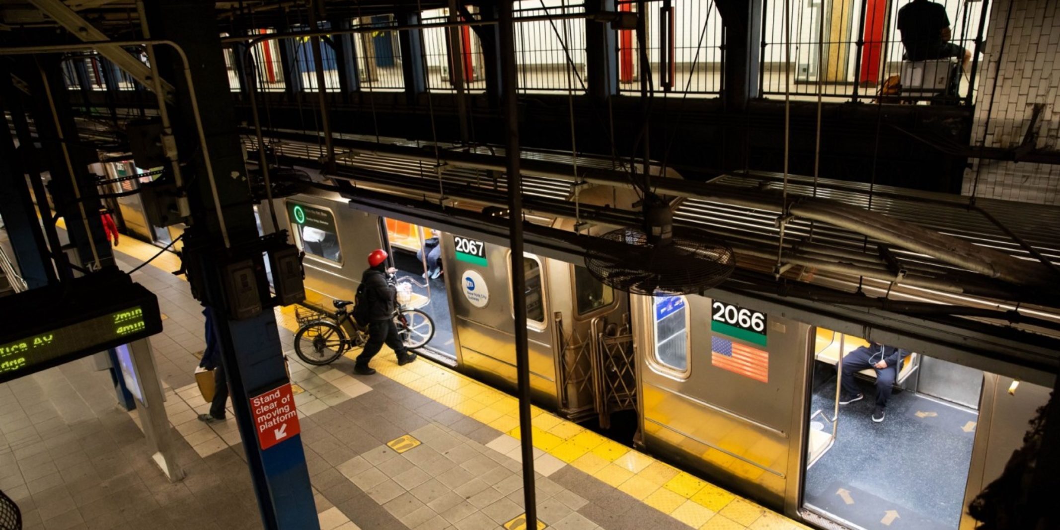 Man with a bike entering a New York City subway car.