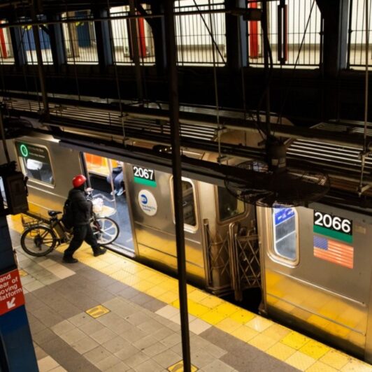 Man with a bike entering a New York City subway car.