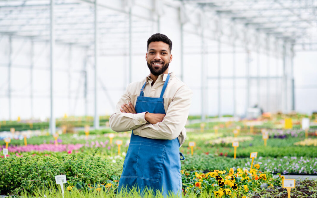 Man working in greenhouse in garden center, looking at camera
