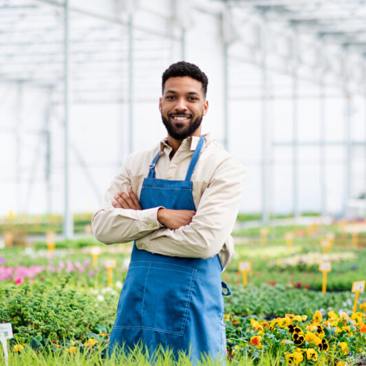 Man working in greenhouse in garden center, looking at camera