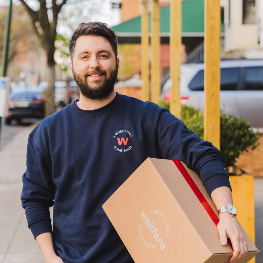 Founder Cole Riley stands on a NYC sidewalk with a cardboard Better Box in his arms