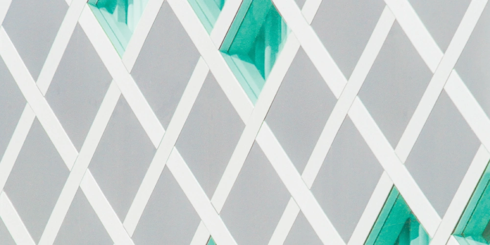 Abstract architectural pattern of white diagonal beams with turquoise glass panels.