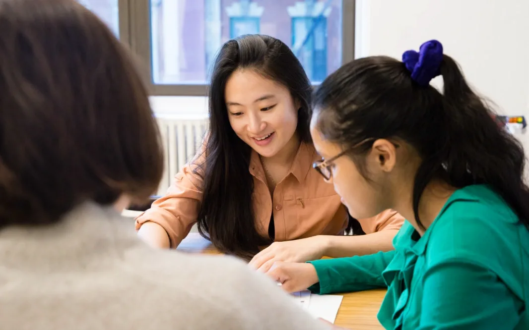 Three people collaborating around a table while reviewing work together.