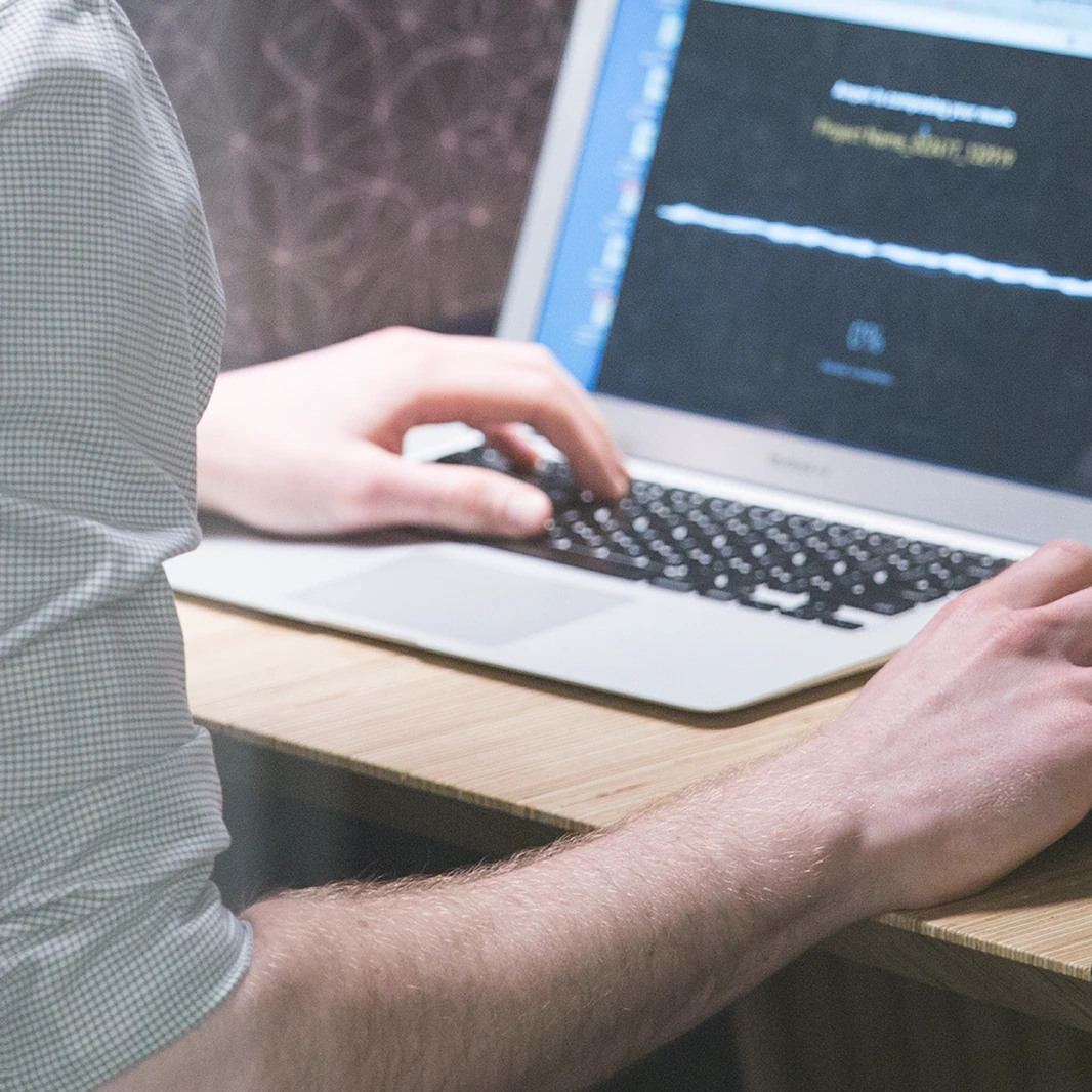 Close-up of hands typing on a laptop keyboard displaying a financial chart with an upward trend line.