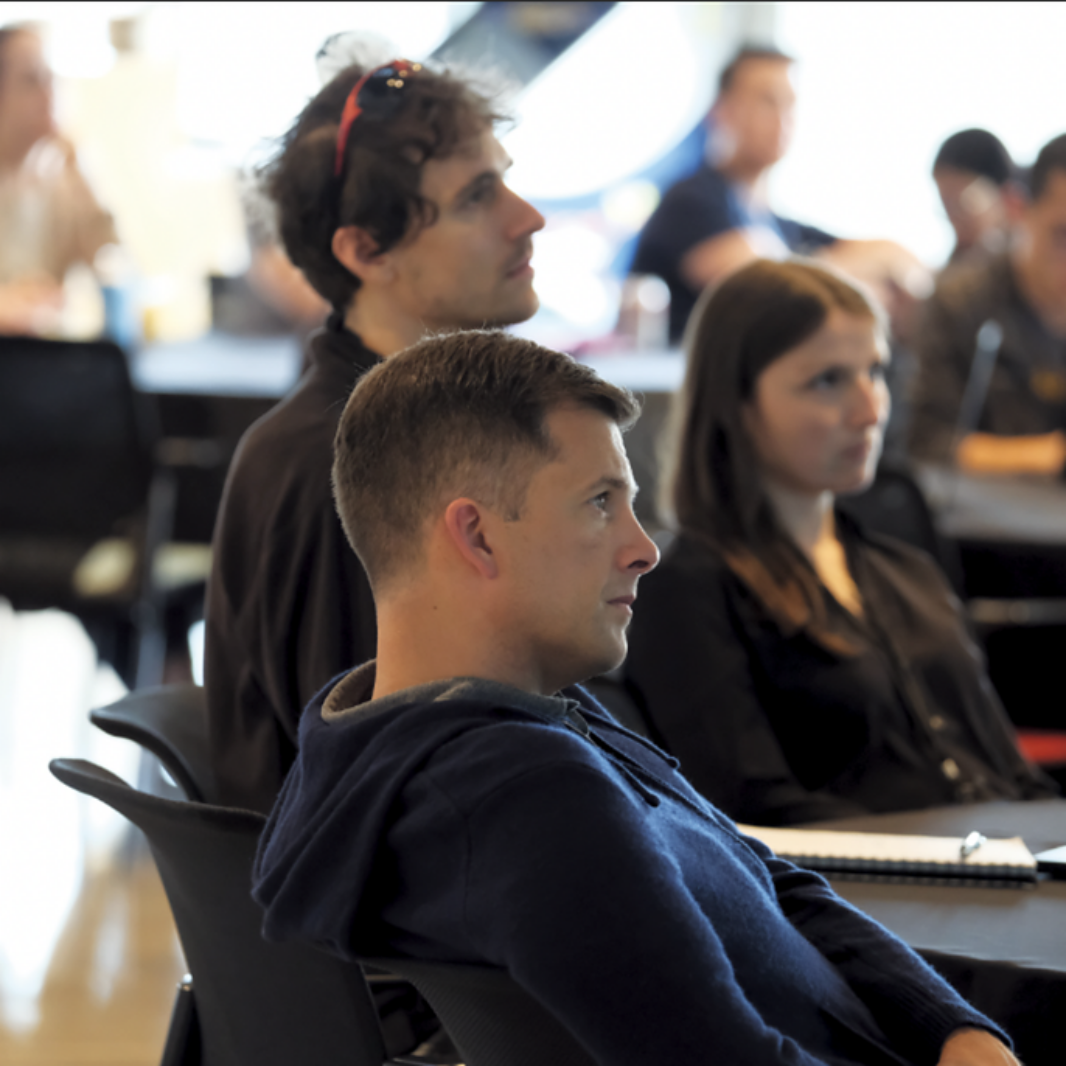 Attendees seated in profile listening attentively at a conference or symposium session.
