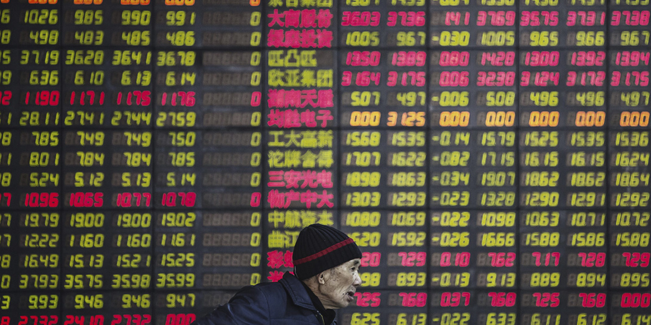 Man in front of stock indexes board