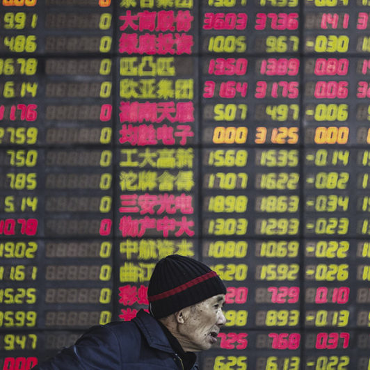 Man in front of stock indexes board