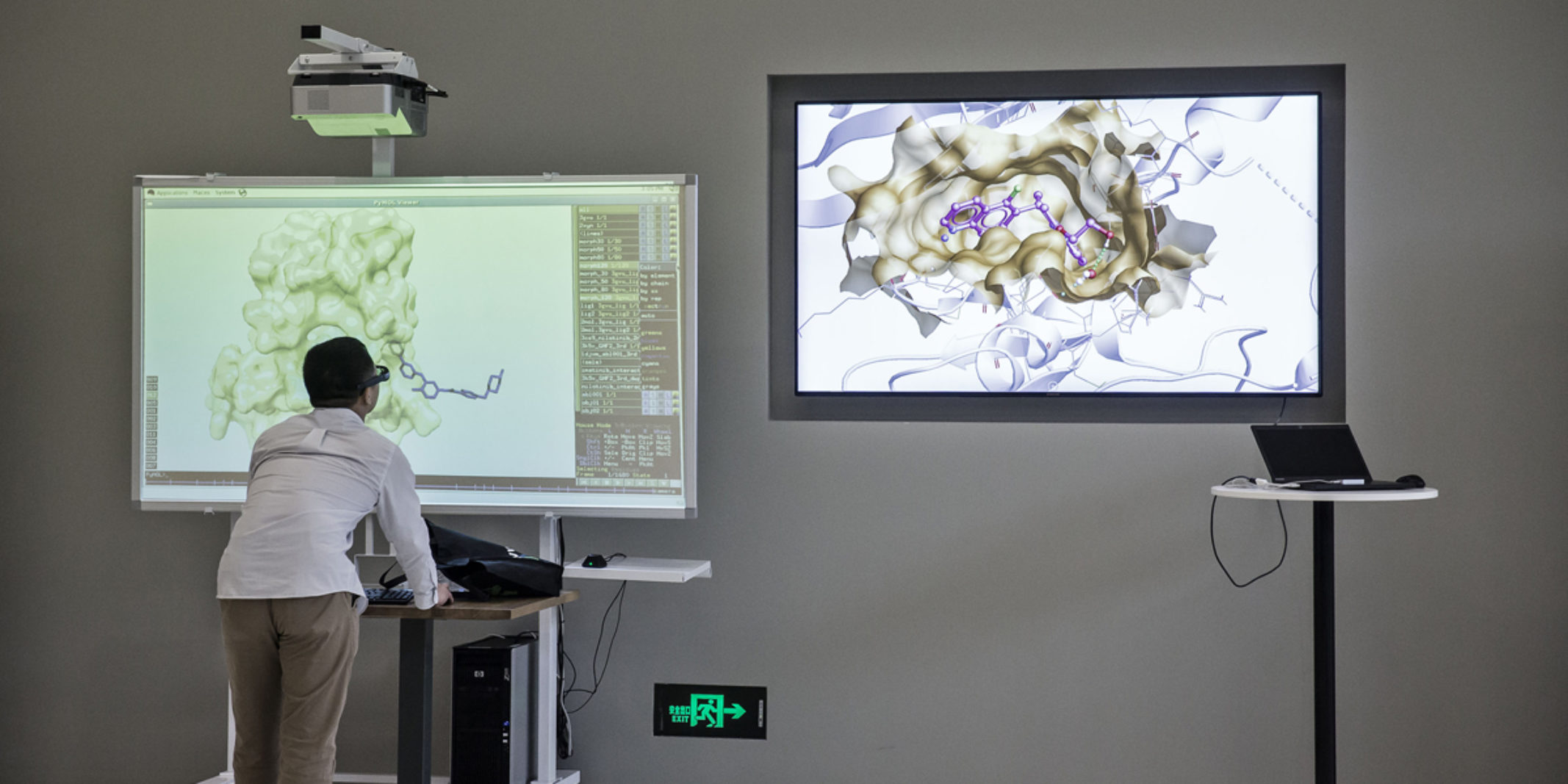 A man looking at a smart board with images of data molecules