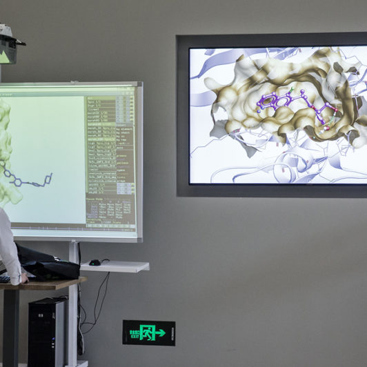 A man looking at a smart board with images of data molecules