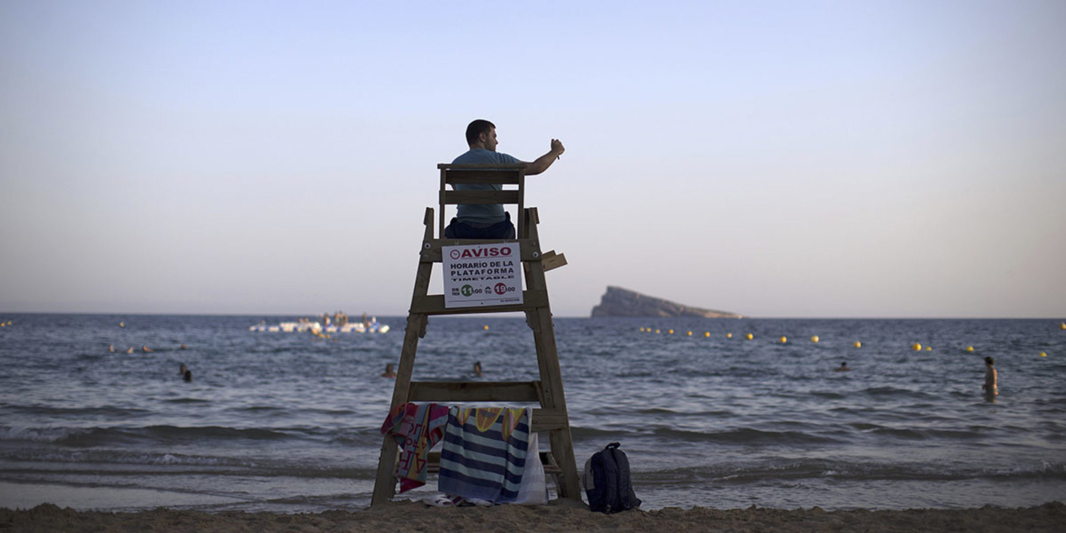 Picture of a lifeguard while he sits on his chair looking into the water