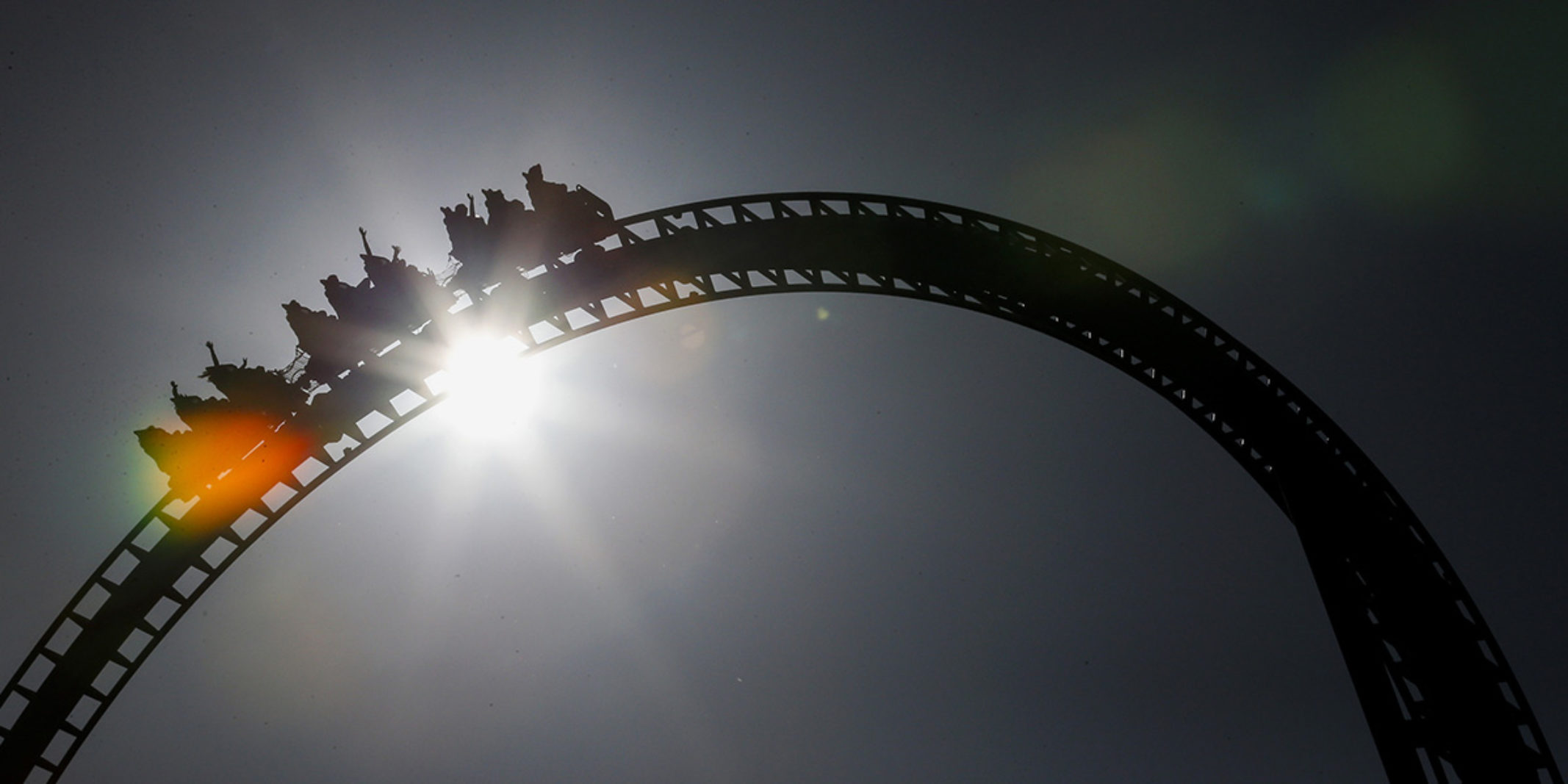 picture of a rollercoaster in motion with the sun behind it
