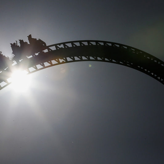 picture of a rollercoaster in motion with the sun behind it